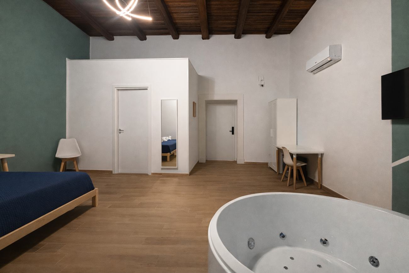 Camera ampia con vasca idromassaggio nell’angolo e travi a vista