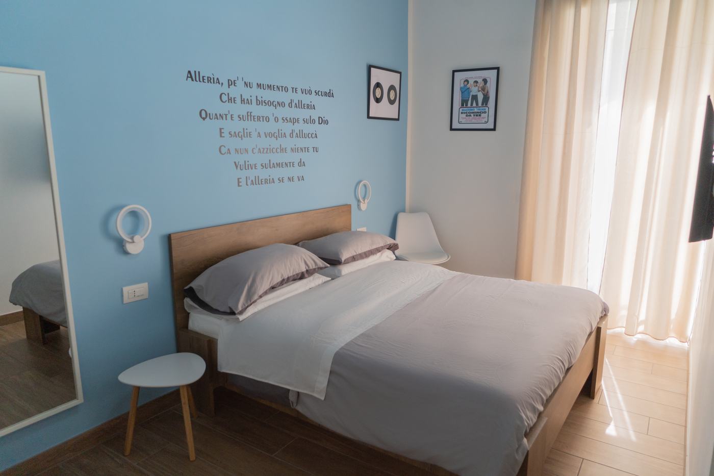 Alleria: letto matrimoniale, parete azzurra e specchio a tutta altezza