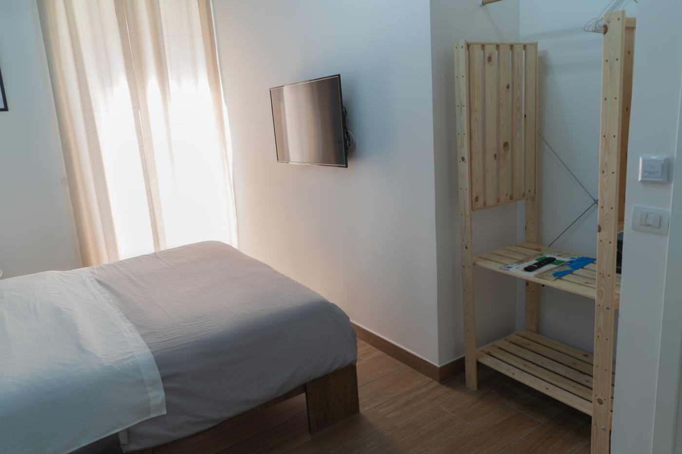 Camera nel centro storico, letto e scaffale in legno con le mappe della città
